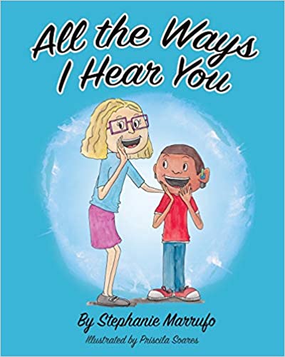 The cover of the book "All the Ways I Hear You" features a bright blue background with the title at the top. An illustrated smiling girl with glasses is talking to a young boy and has her left hand on his shoulder. The smiling boy is wearing hearing aids.