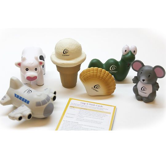 A set of 6 toys sitting on a white table: airplane, cow, ice cream cone, shell, snake, and koala. Toys positioned around a card with the title "Ling-6 Flash Cards" at the top.