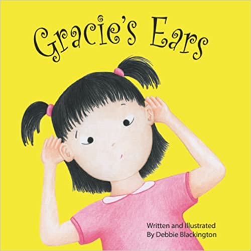 The cover of the book "Gracie's Ears" features a yellow background with the title at the top. An illustrated young girl wearing a pink shirt has both hands behind her ears.