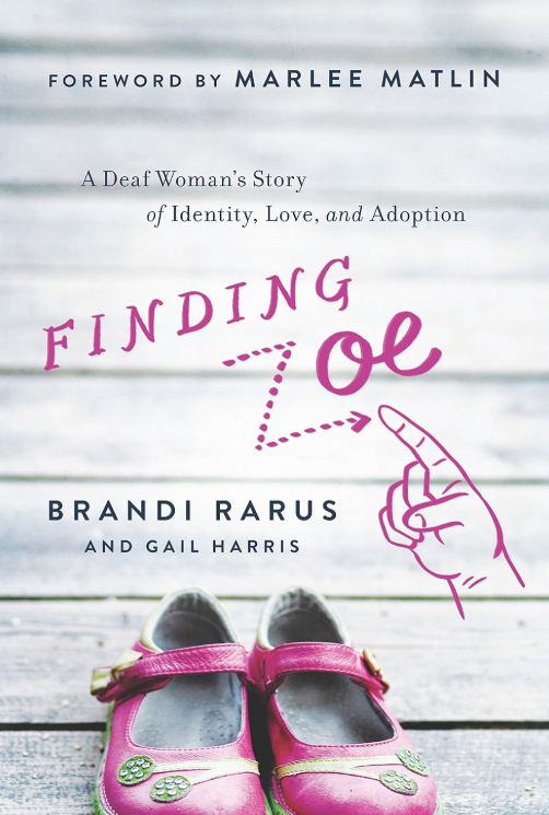 The cover of the book "Finding Zoe: A Deaf Woman's Story of Identity, Love, and Adoption" features a gray background with a pair of pink girl shows at the bottom.