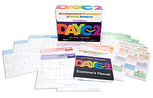 An image of the items included in the Developmental Assessment of Young Childen -  Second Addition assement kit. The box sits in the center with several testing record forms spread around the box. The manual also is laying in front of the box with the acronymn DAYC-2 on the cover.
