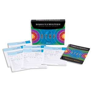 A colorful box with the DTAP stands upright in the back. Laying in front of the box are paper copies of the test record sheets and the spiral bound examiner's manual for the Developmental Test of Auditory Perception assessment.