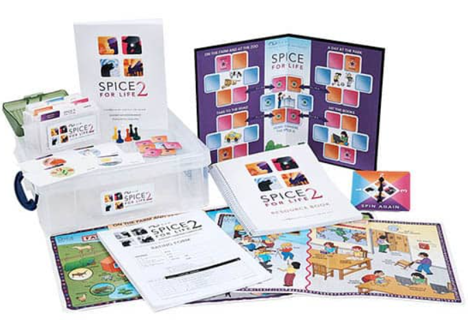 A snapshot of the SPICE for Life 2 auditory learning curriculum items including the clear storage box with the manual and picture cards sitting on top of it. In front, the large listening scene cards are spread out with the rating forms and resource book. The game board, spinner, and game tokens are to the right.