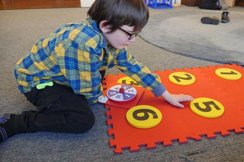 Picture of child playing on Hop-A-Dot mat with number spinner