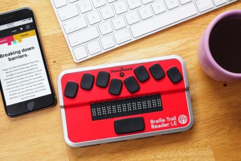 Braille Trail Reader with keyboard, coffee and smartphone.
