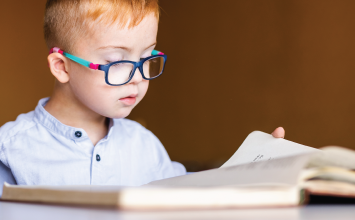 Young boy with glasses reading a book